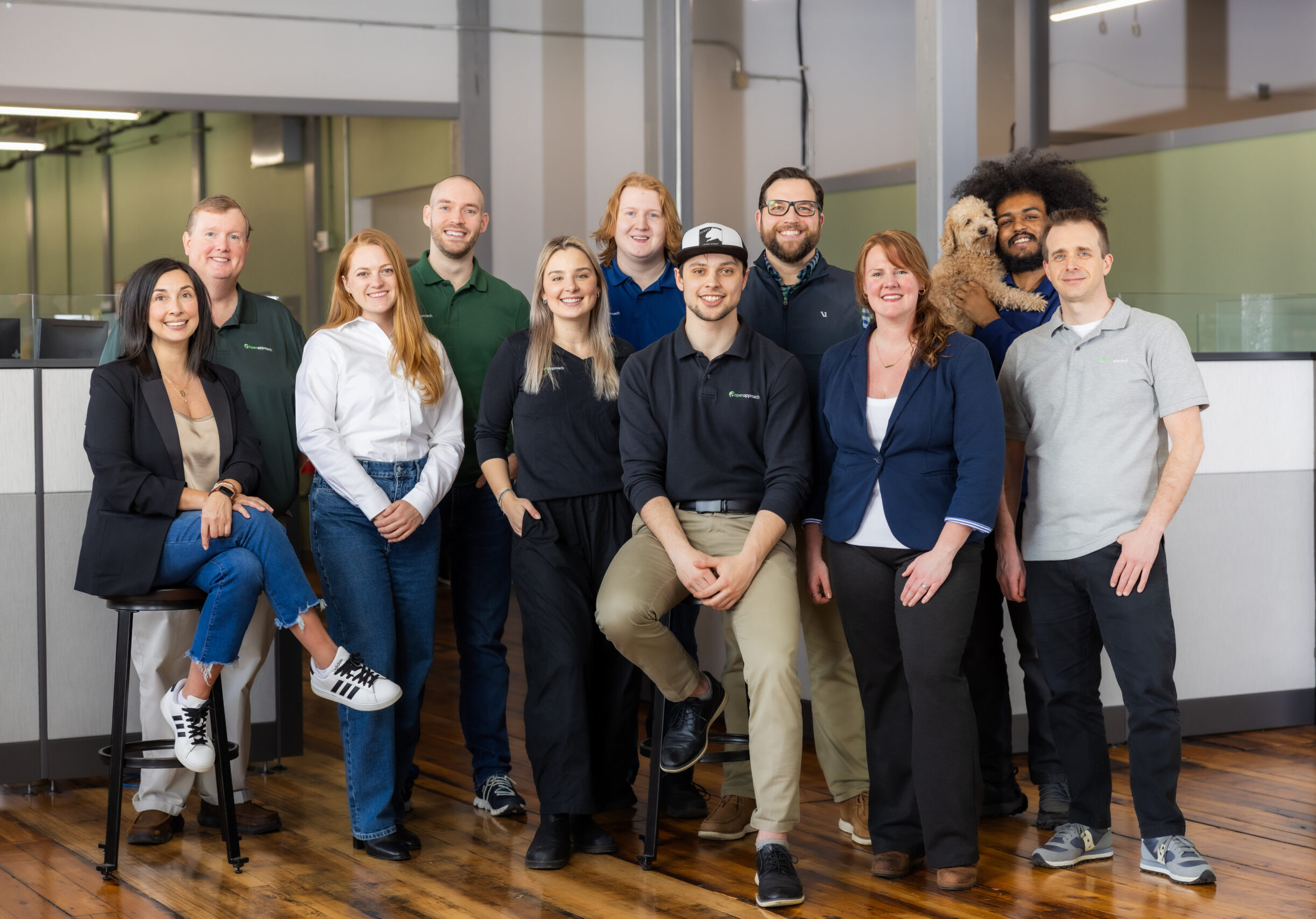 group of people standing in an office space, facing the camera and smiling