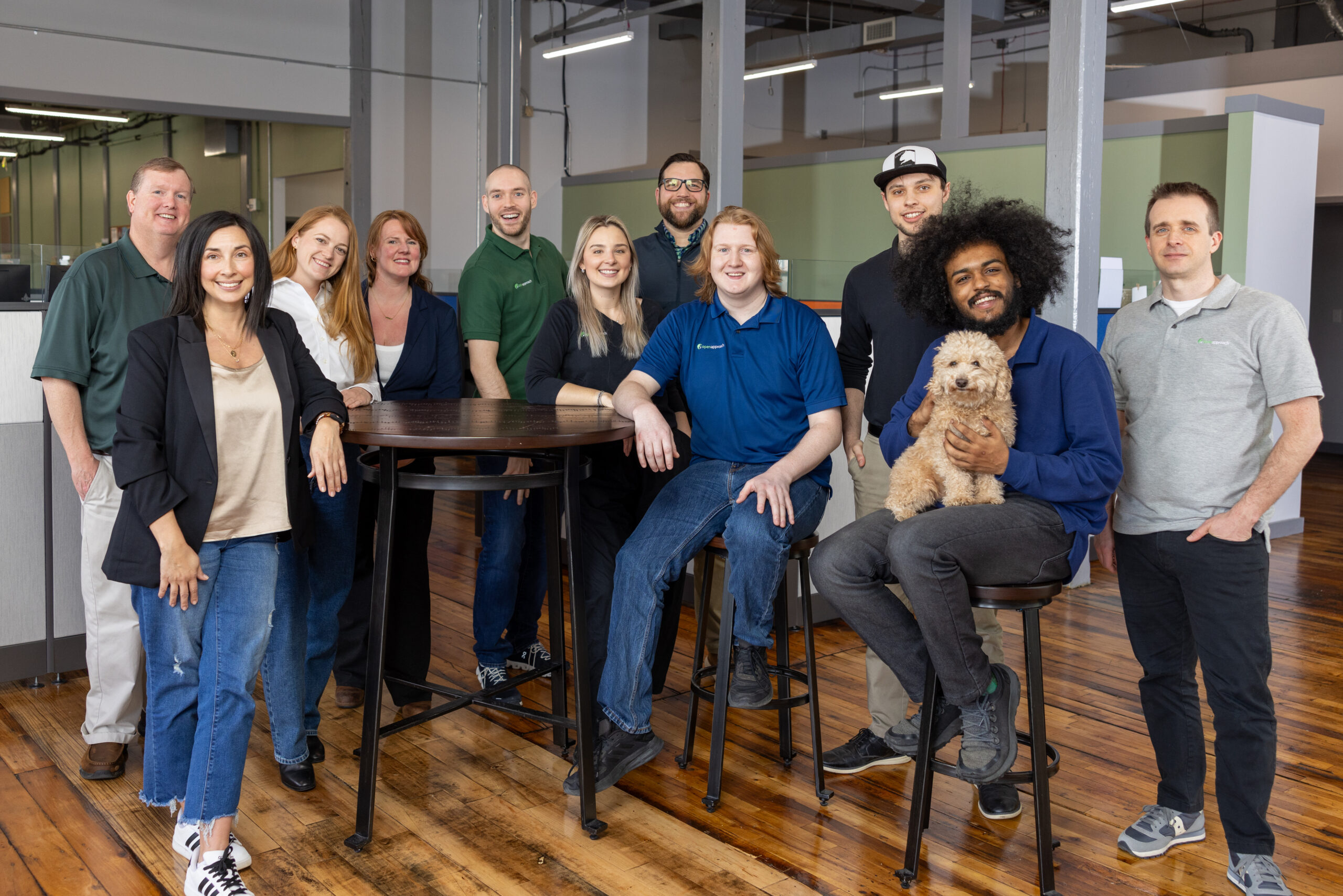 group of people standing in an office space, facing the camera and smiling
