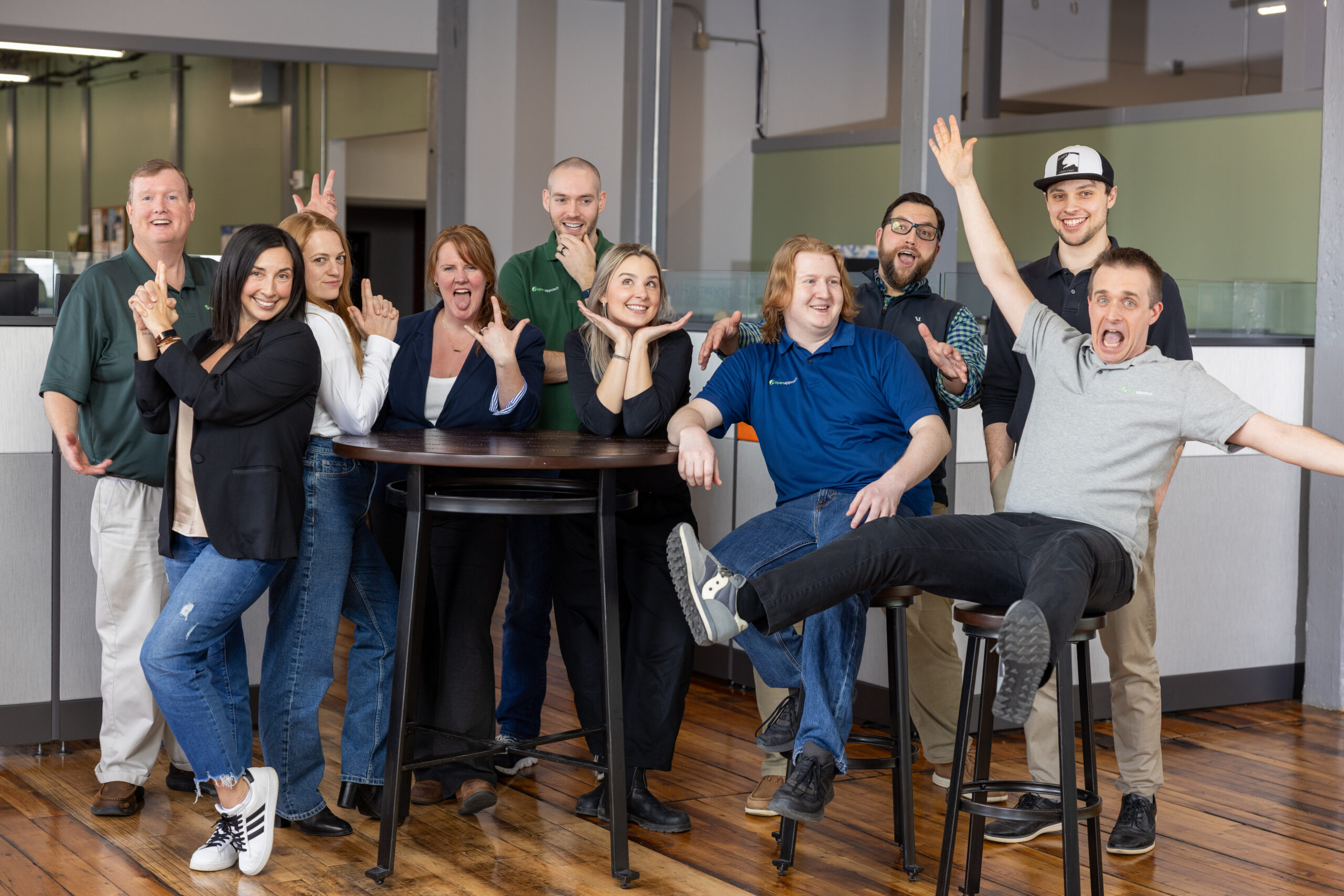 group of people in an office space, facing the camera and looking goofy and smiling